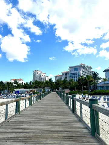 A point of view shot from a pier leading to the sandy shores before Baha Mar Hotel on a sunny day. 