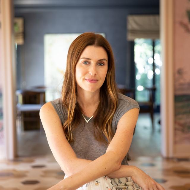 Zoe Schaeffer Travel Agent wearing gray shirt in open room with brown and white tiles