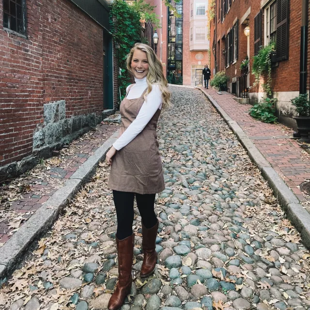 Travel Advisor Natalie Bell in a brown dress and white turtleneck on a cobblestone street.
