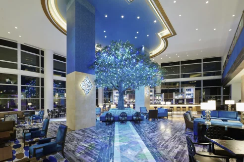 blue-lit lobby with an illuminated decorative tree