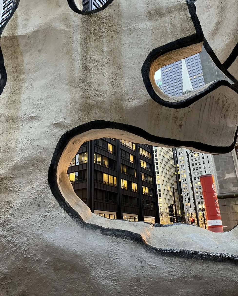 a city seen through an abstract stone-like sculpture 