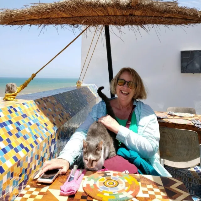 Travel advisor Carol Johnston petting a cat on a sunny terrace