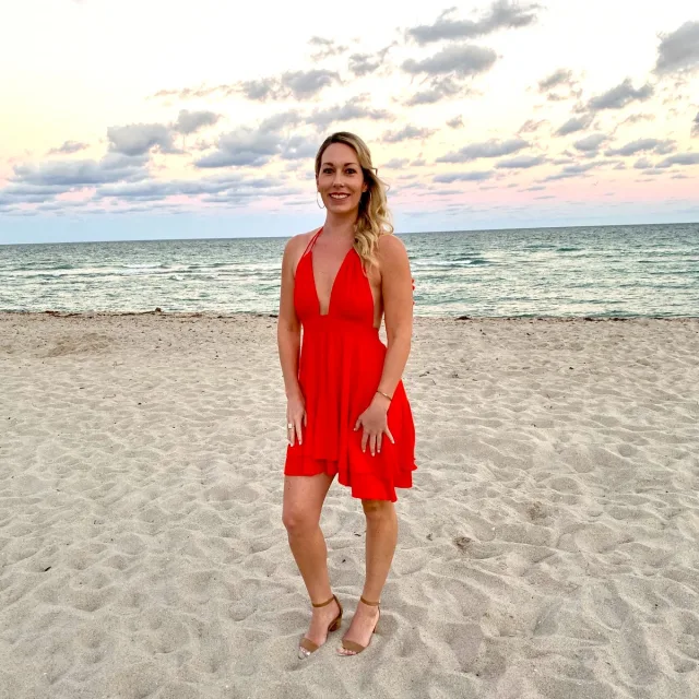 Travel Advisor Sadie Bauer in a red dress on a beach at sunset.