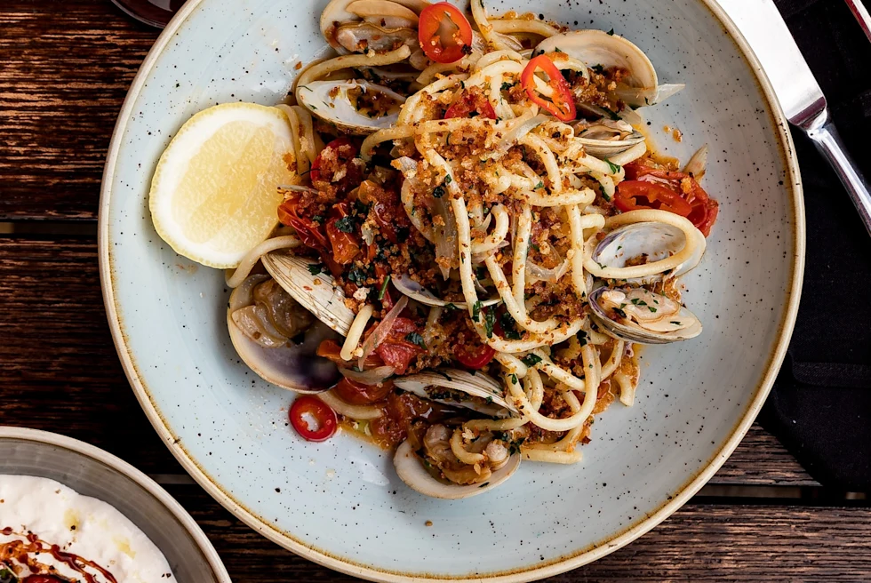 Spicy seafood pasta on a dinner table with wine.