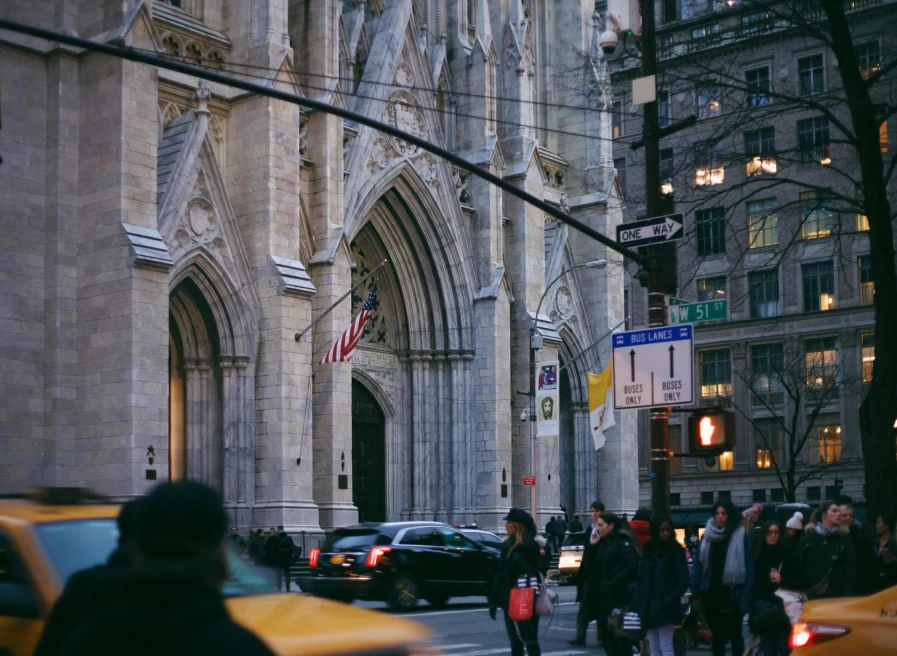 stone cathedral next to people and yellow taxis
