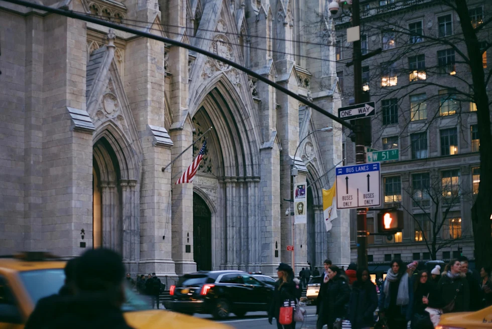 stone cathedral next to people and yellow taxis