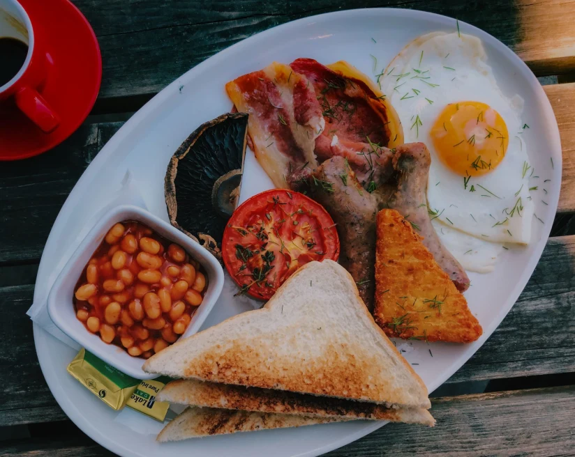 a plate with classic english breakfast of beans, eggs and sausage