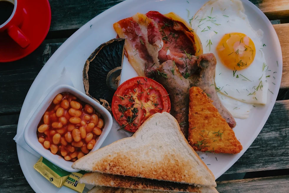 a plate with classic english breakfast of beans, eggs and sausage