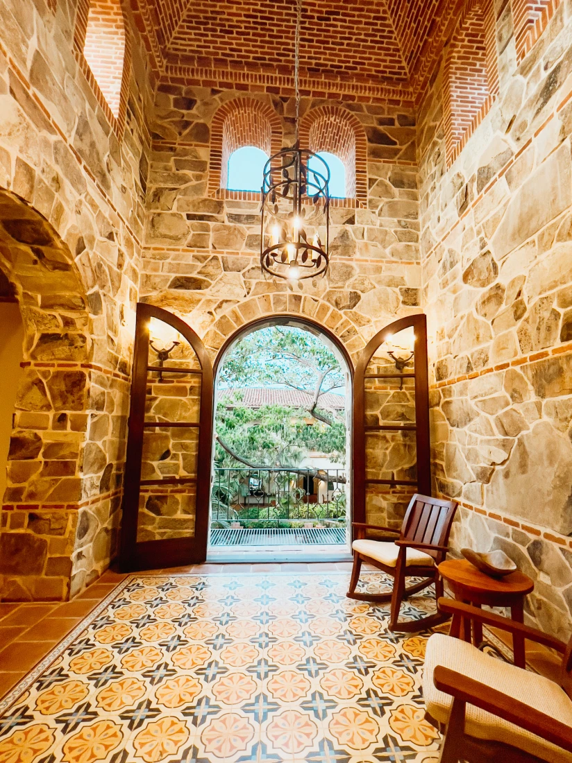 Inside the lobby of Rancho Santana Inn, featuring tiled floors, stone walls, and a grand hanging lighting fixture.