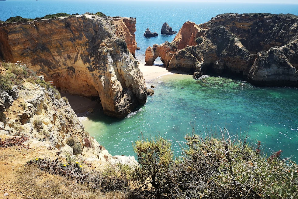 A sea with blueish green water surrounded by big rocks.