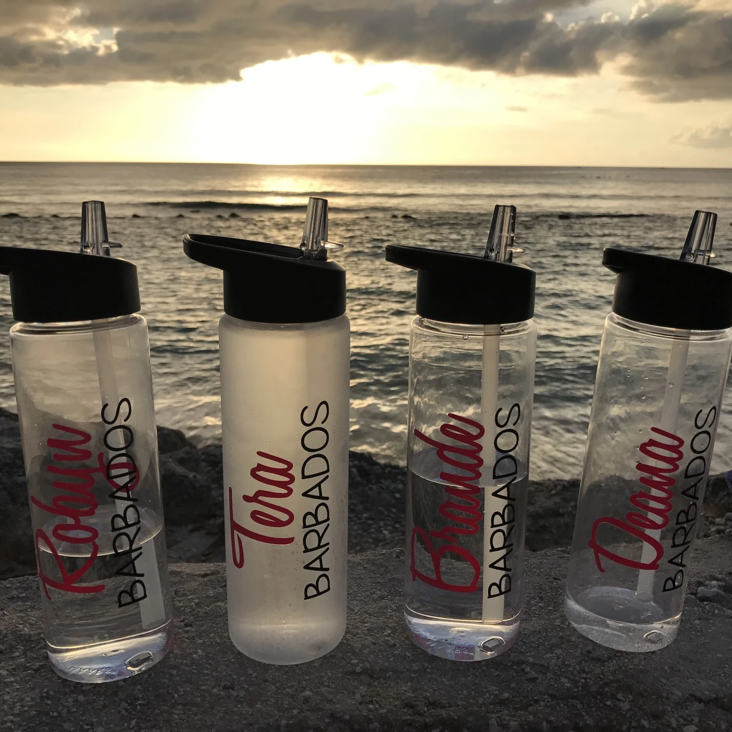 Four water bottles on a beach.