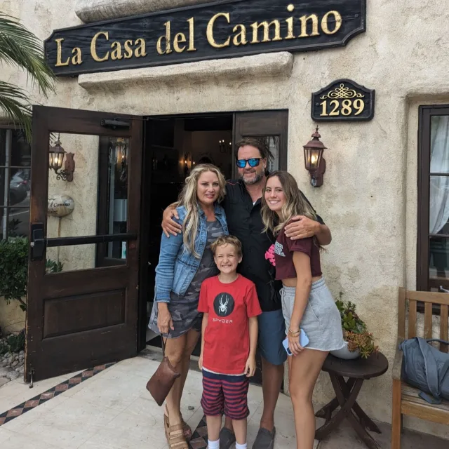 A photo of a family in front of a building with a sign that reads "La Casa del Camino"