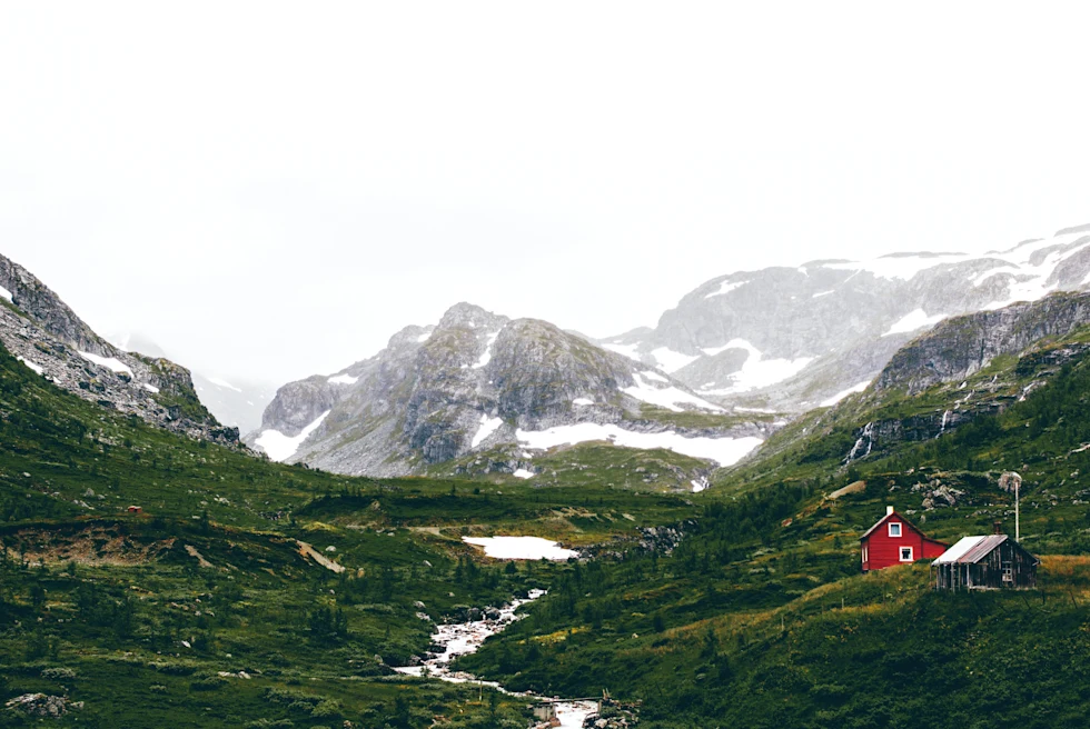 Snowy mountains and green valley with cloudy skies during daytime