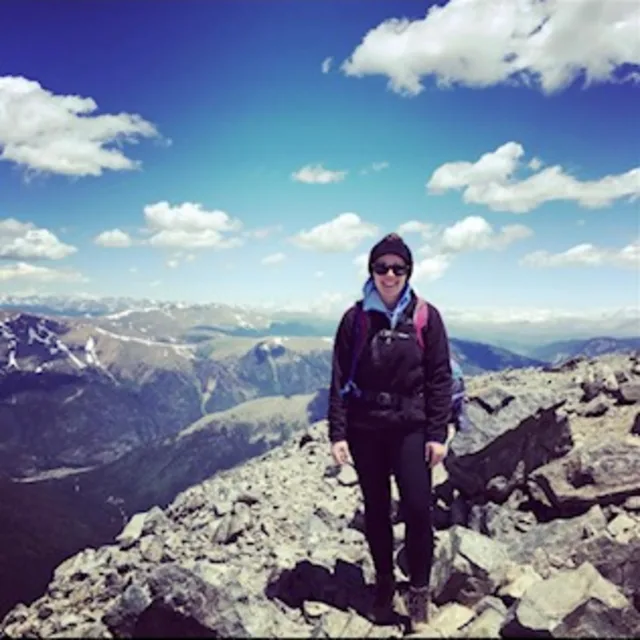 Travel advisor Laura Miller standing in a mountain wearing sun glasses and backpack.