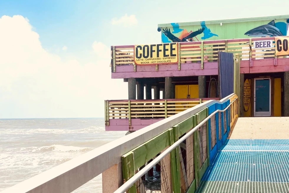 A colorful building with a sign Coffee near ocean. 