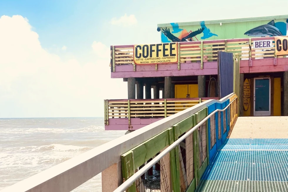 A colorful building with a sign Coffee near ocean. 