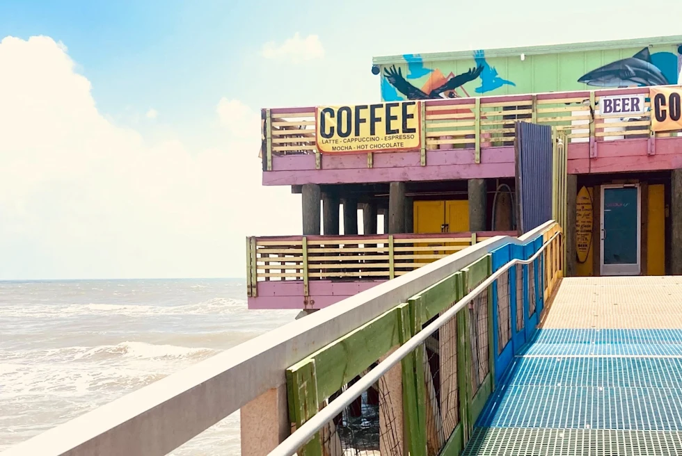A colorful building with a sign Coffee near ocean.