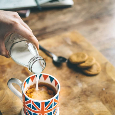 A cup with the British flag on it with black tea and milk. 