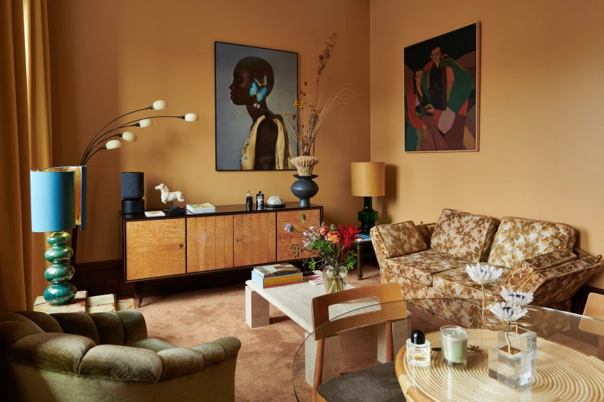 a stylish living room with a patterned couch, yellowish orange walls and colorful artwork