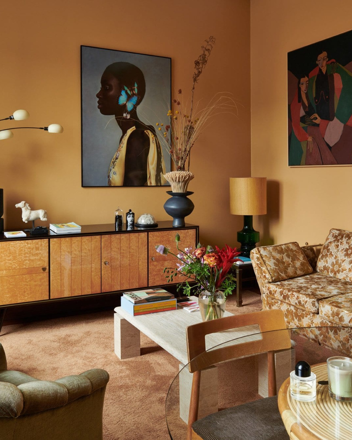 a stylish living room with a patterned couch, yellowish orange walls and colorful artwork