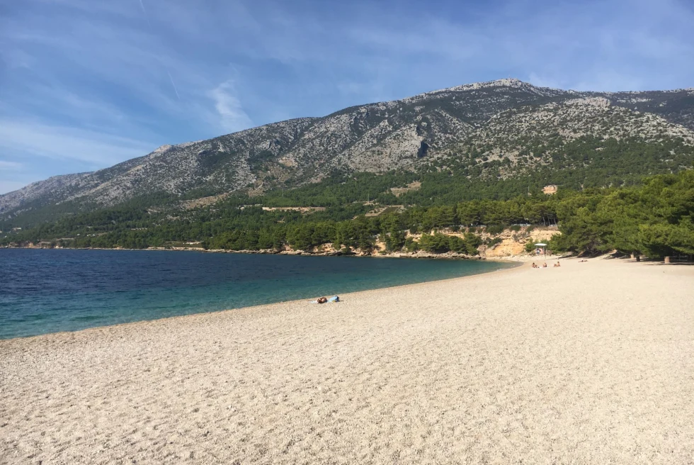 calm white sand beach with mountains behind 