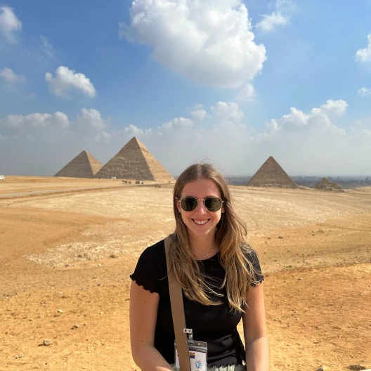 Travel advisor Eliza Jameson in black shirt in front of Egypt pyramids.