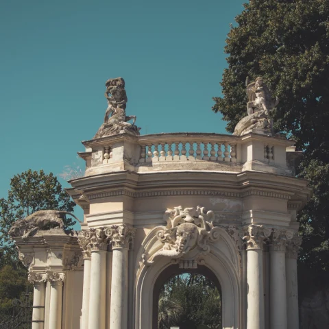 A white arch with statues on top of it.