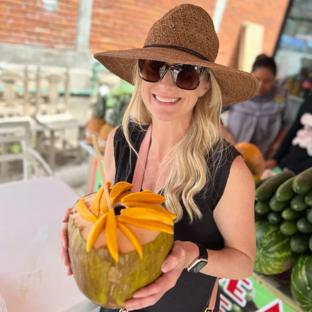 Picture of Nancy wearing a hat and sunglasses with a large coconut in hand
