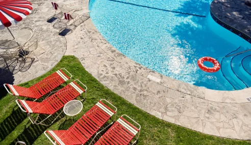 Sunny Austin Motel pool with red lounge chairs and a red inner tube