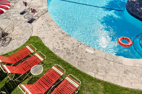 Sunny Austin Motel pool with red lounge chairs and a red inner tube