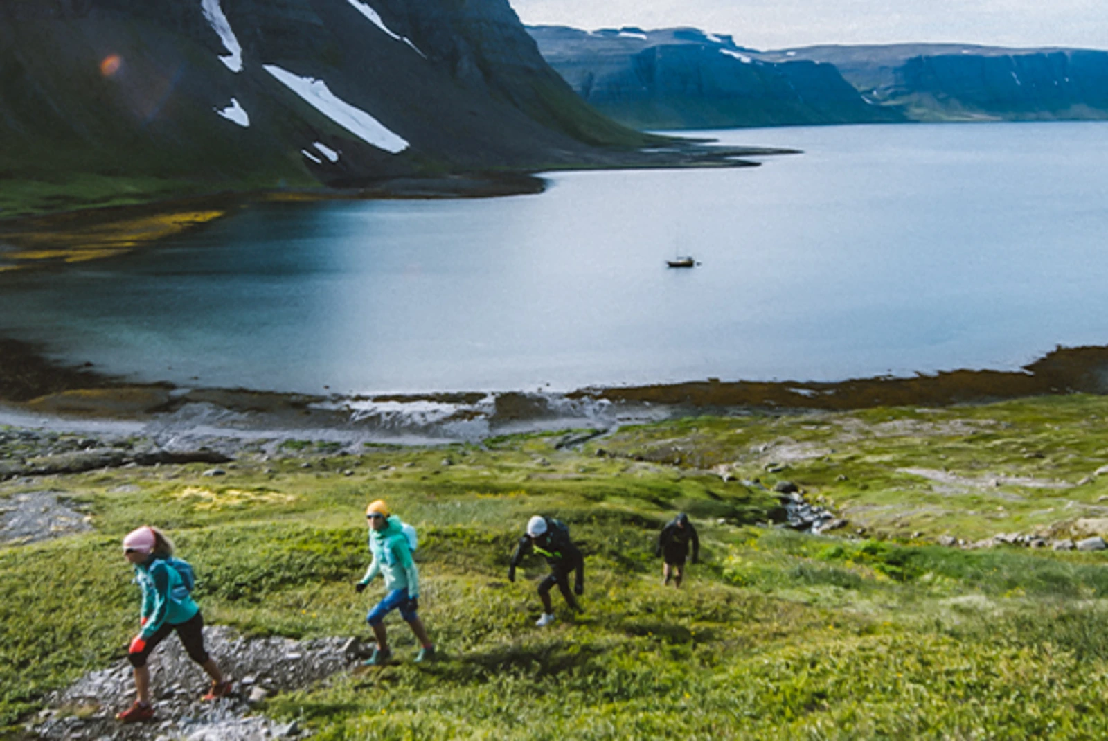 Four people hiking up a grassy hill in Iceland.