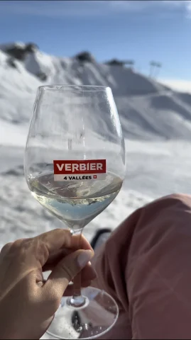 a wine glass in hand at the top of a ski mountain