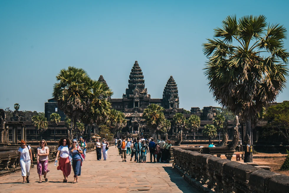 A temple in Cambodia with tourists walking in front.
