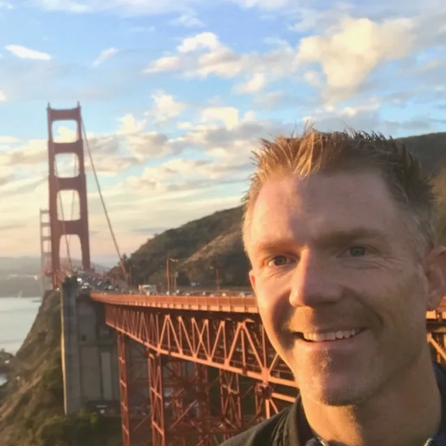 travel advisor John Blevens stands in front of the San Fransisco bridge