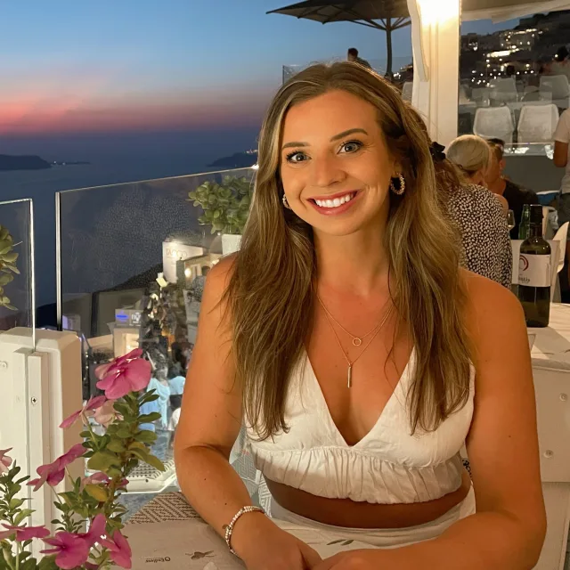 Travel Advisor Madi Philpott in a white dress in front of the sunset.