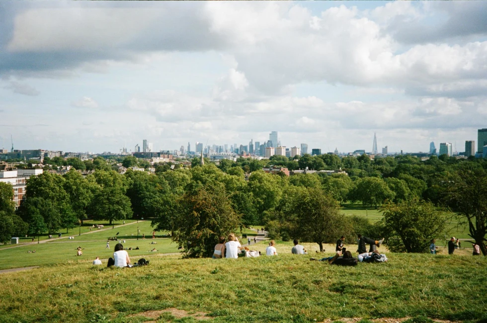 a view of London from the top of a grassy hill on a sunny day