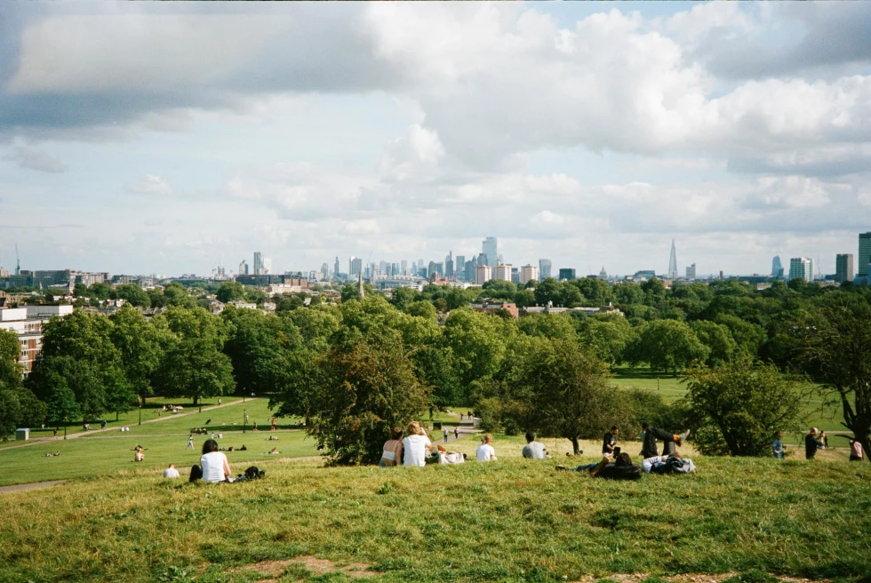 a view of London from the top of a grassy hill on a sunny day