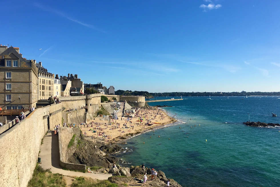 large wall next to buildings and ocean during daytime