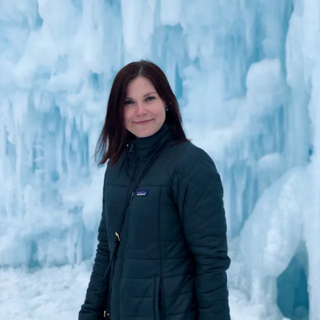 Travel advisor wearing a black coat standing in front of icebergs