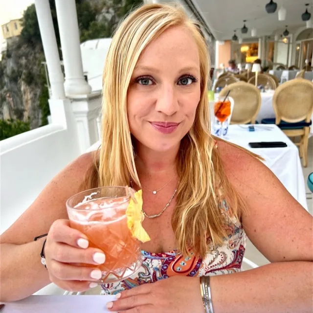 Travel Advisor Mia Booth drinking juice while sitting at a restaurant's terrace.