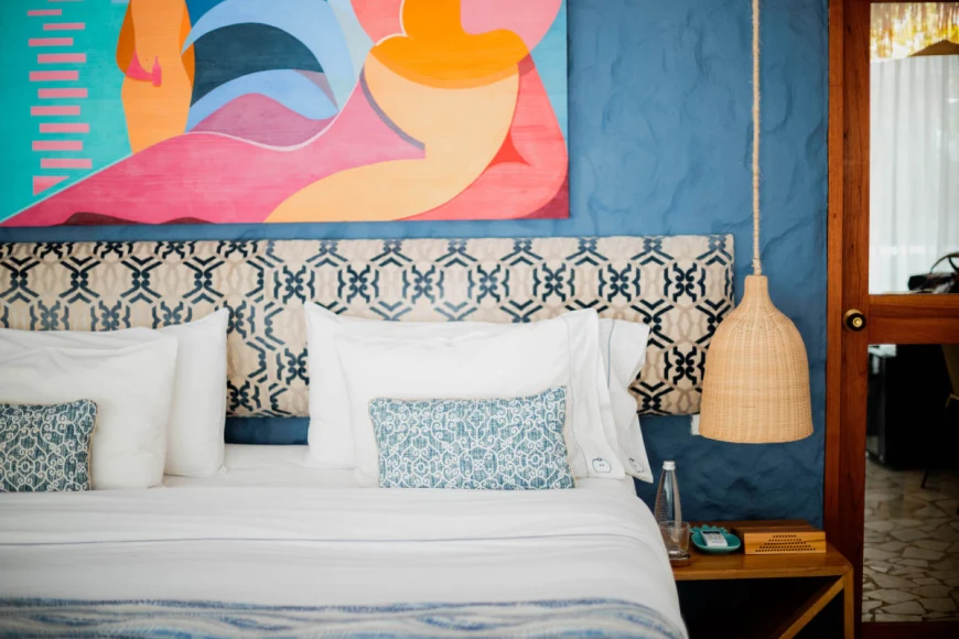 bed against a blue wall with a colorful painting