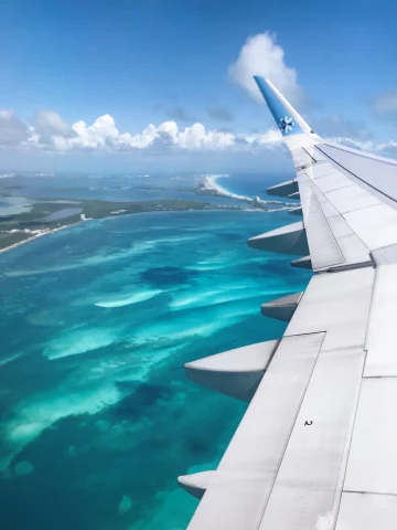 A plane landing over the azure waters of Cancun. 