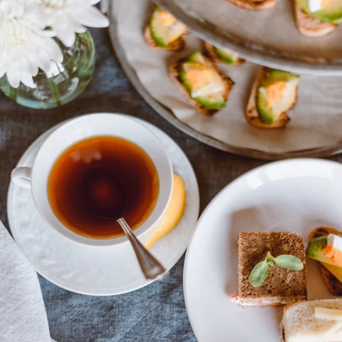 Afternoon tea featuring finger sandwiches, biscuits and black tea. 