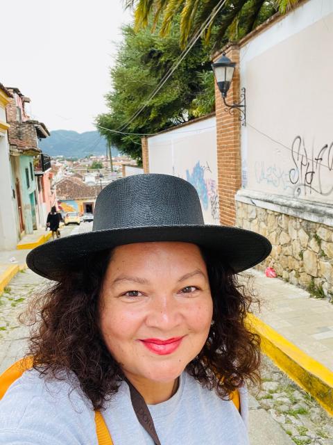 Travel agent Alma Lopez wearing a black hat standing on cobblestone street