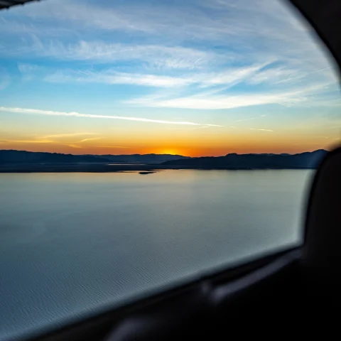 sunset over a pristine lake from the view of a car window