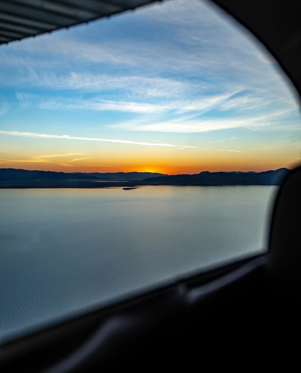 sunset over a pristine lake from the view of a car window