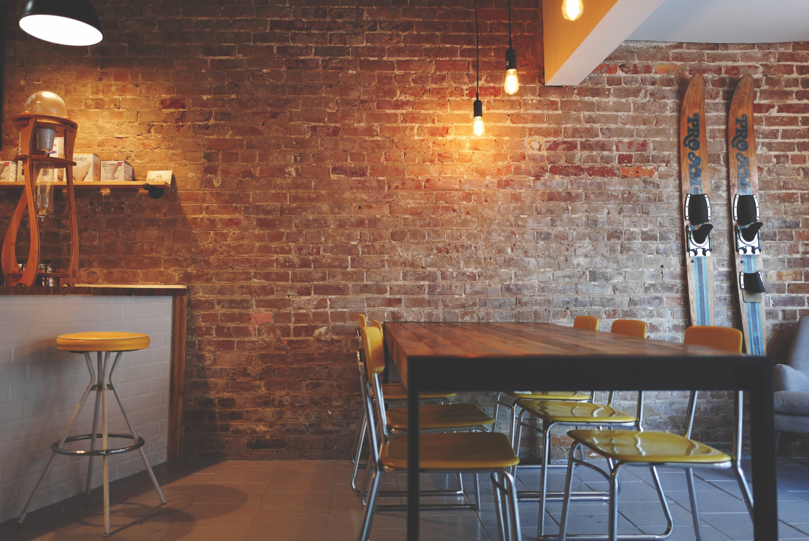 Table with chairs next to brick wall with skis leaning against the wall