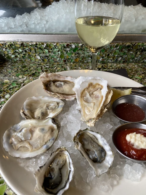 White bowl of oysters next to a glass of white wine