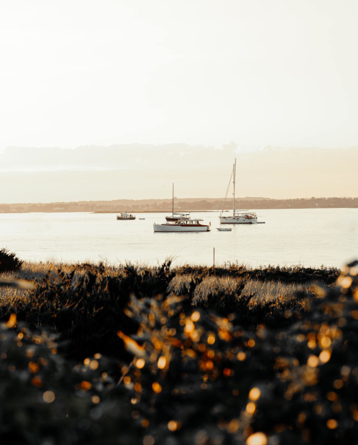 Boats floating on bay during sun rise on a cloudy day in Westerly, RI.