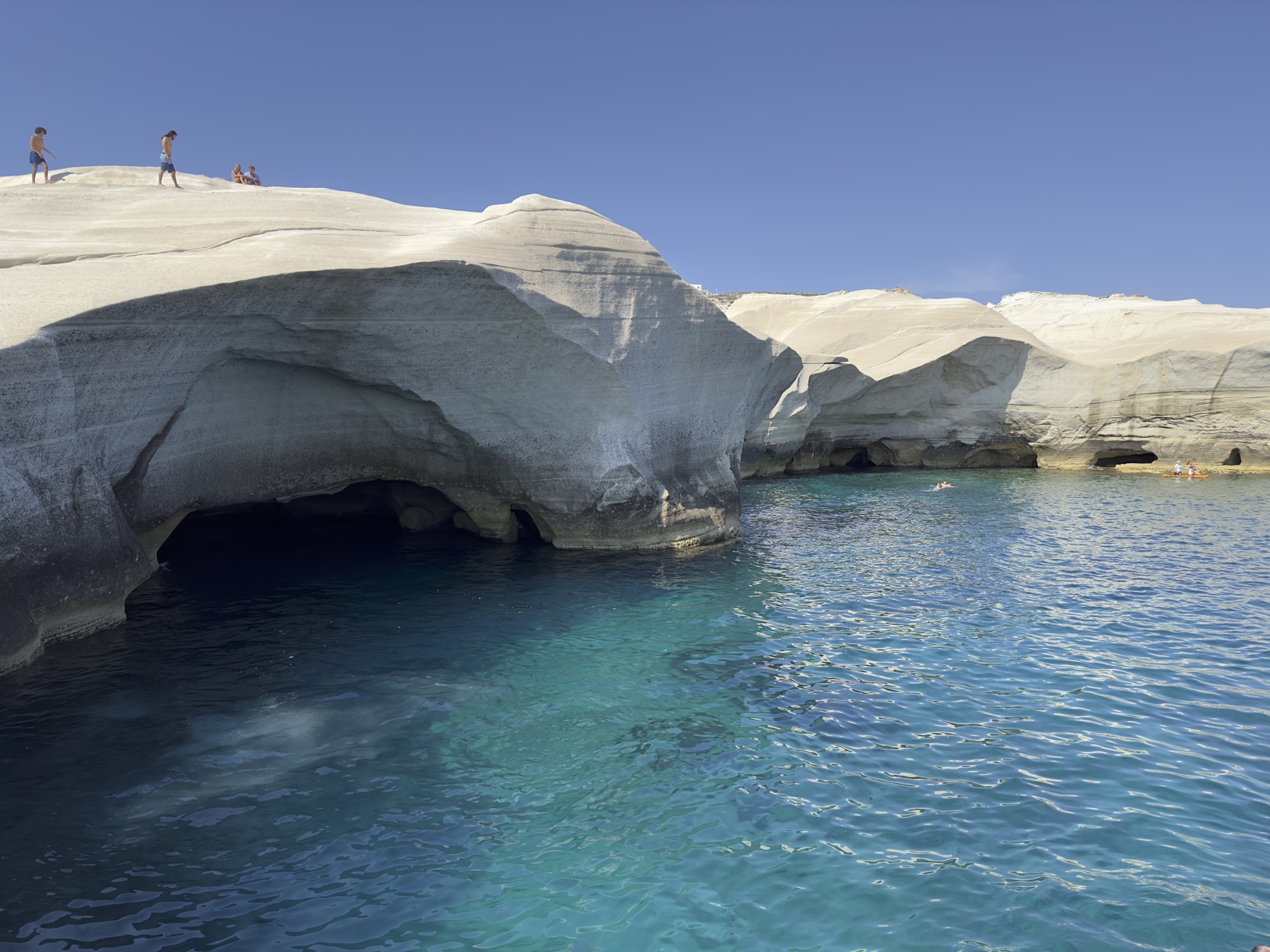 People on a cliff edge on a beach.